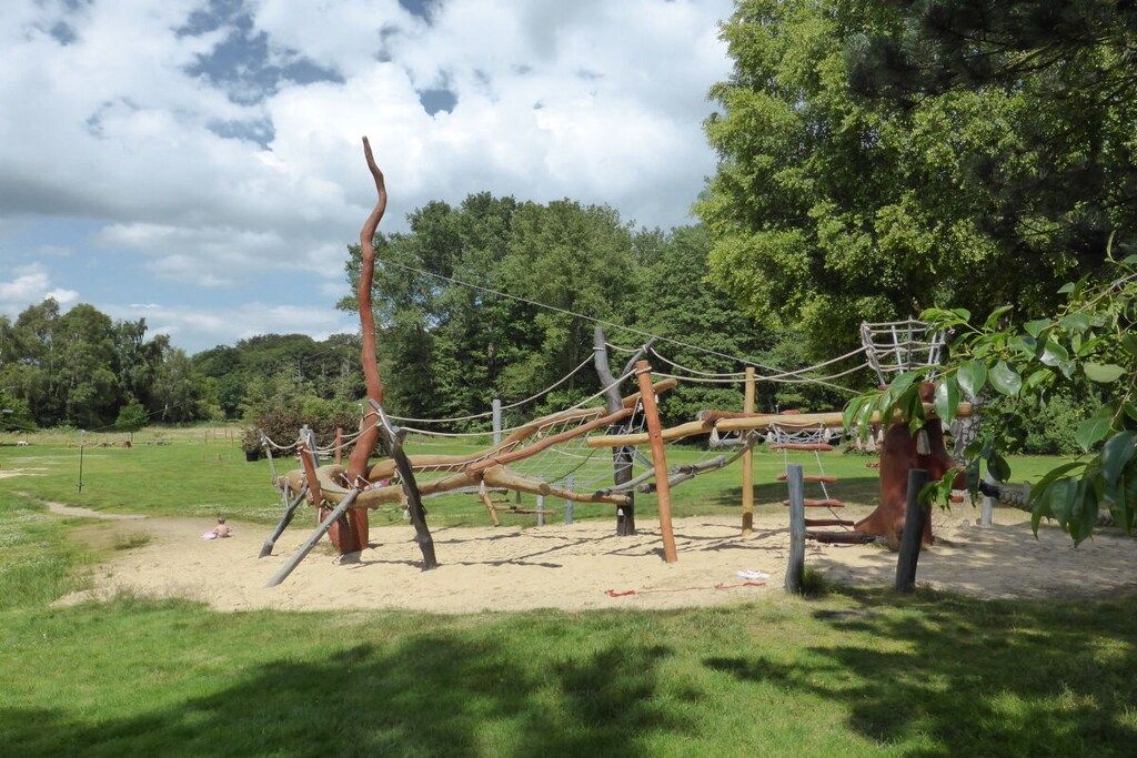 An outdoor playground with climbing structures and a rope bridge.