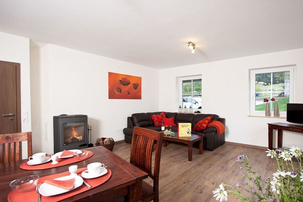 A cozy living room with a fireplace, a dining area with a table set for two, and a comfortable sofa.