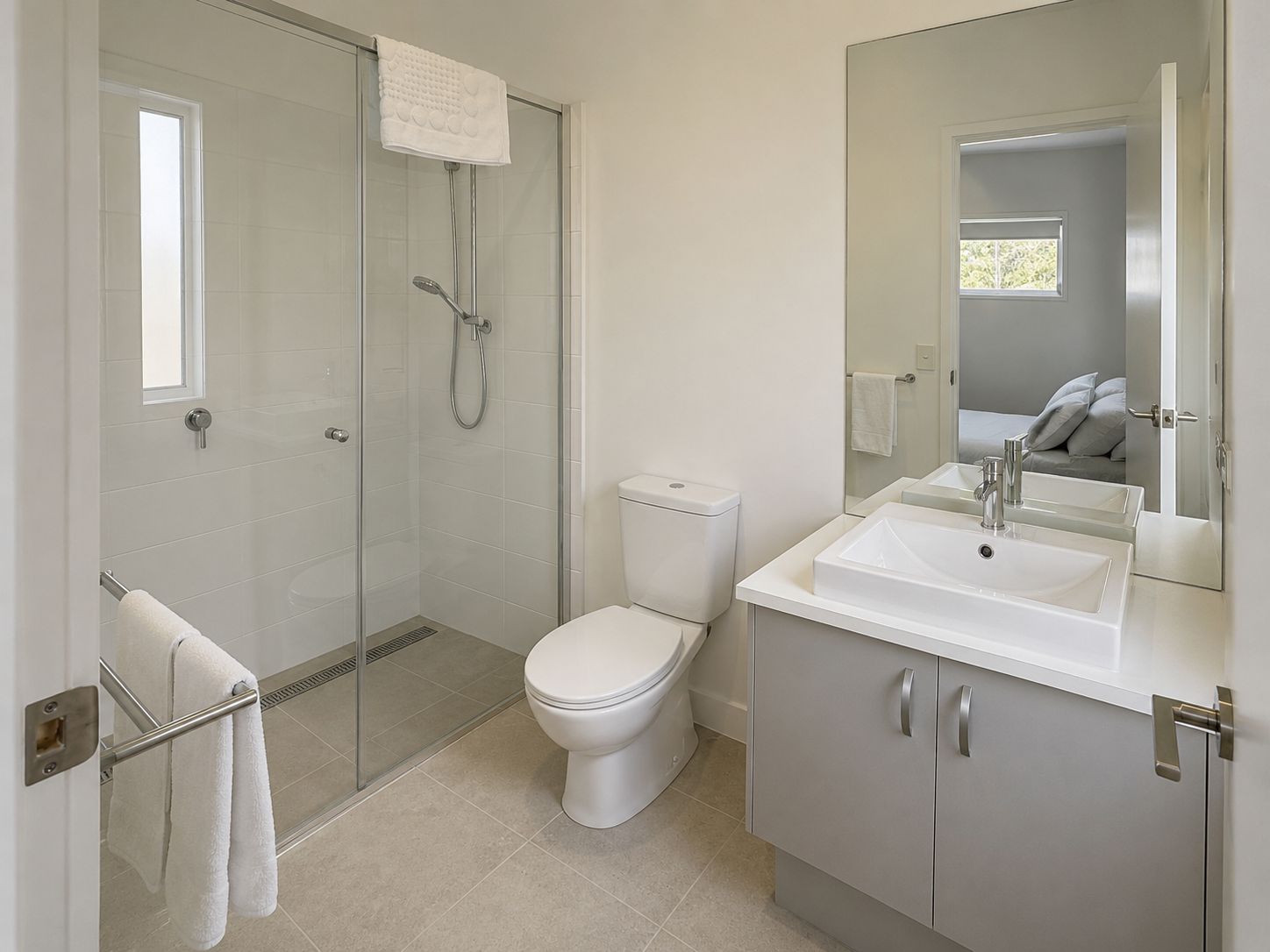 Een moderne badkamer met een glazen douchecabine, een toilet en een wastafel met spiegel.