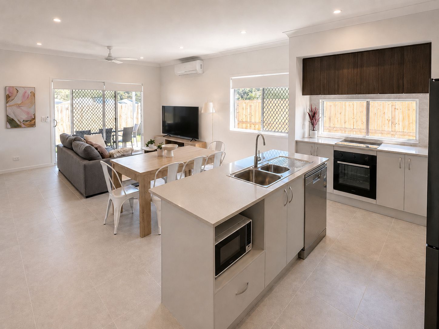 A modern kitchen with a central island, built-in oven, and a dining area with a sofa and chairs.