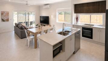 A modern kitchen with a central island, built-in oven, and a dining area with a sofa and chairs.