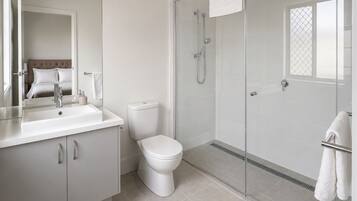 A modern bathroom with a toilet, sink, and shower.