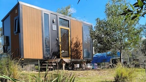 A modern mobile home with a wooden exterior, a sliding door, and a small porch area.