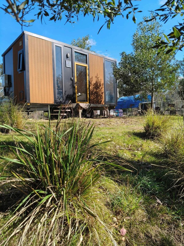 A modern mobile home with a wooden exterior, a sliding door, and a small porch area.