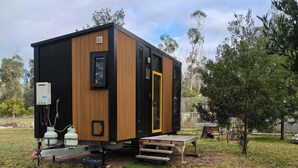 A stationary, modern, single-story cabin with a wooden exterior, a black door, and a small porch area.