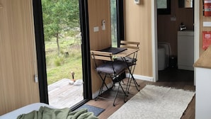 A room with a bed, a folding table, and a view of the outdoors.