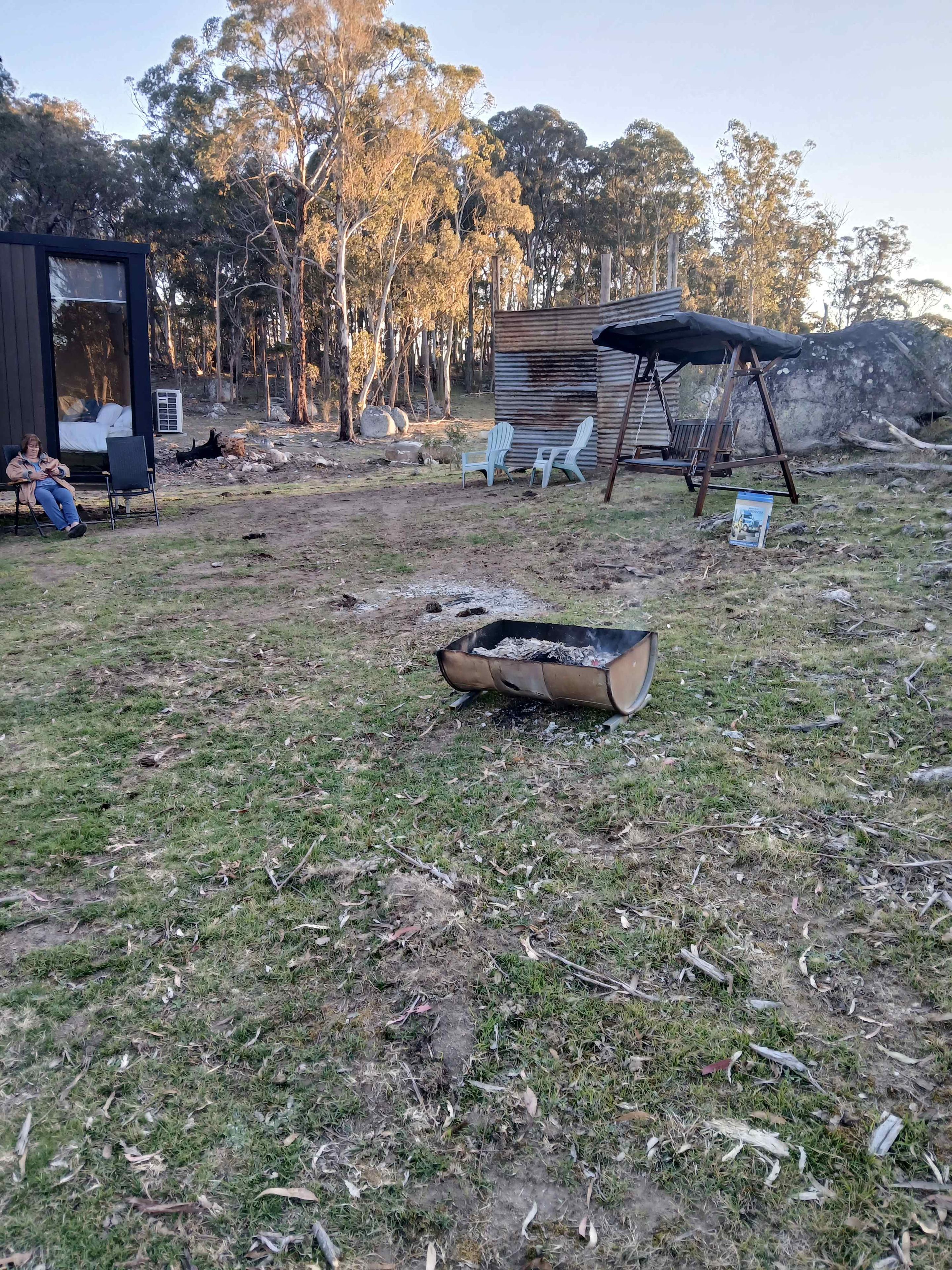 Un jardin avec une terrasse en bois, une balançoire et un barbecue.