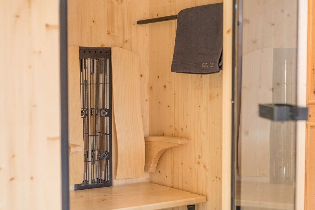 Un interior de madera con una puerta metálica, una toalla colgada y una puerta de vidrio.