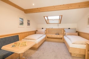 A room with two wooden beds, a bench, a small table with a chessboard, and a skylight. - Holiday apartment in Oberstdorf with balcony (Oberstdorf)