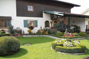 Ein Haus mit einem gepflegten Garten, der verschiedene Blumenbeete und Sträucher zeigt.