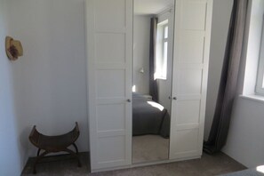 Ein Zimmer mit Schrank, Stuhl und Bett.