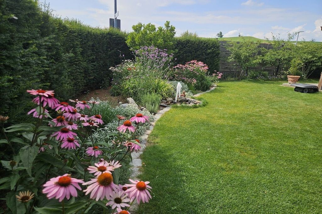 Un jardín bien cuidado con diversas flores y un césped impecable.