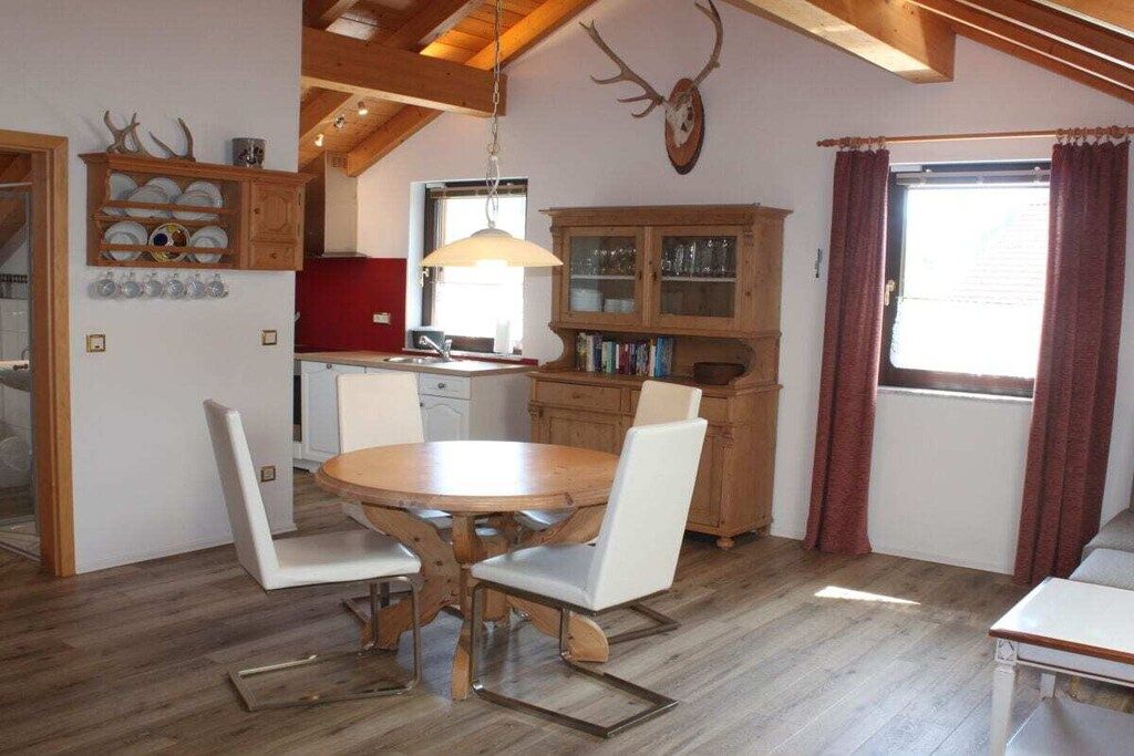Un comedor con una mesa y sillas de madera, una cocina con armarios de madera y una cabeza de venado montada en la pared.