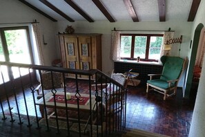 A room with a wooden staircase, a green armchair, and a fireplace. - Holiday home on Lake Chiemsee (Breitbrunn am Chiemsee)