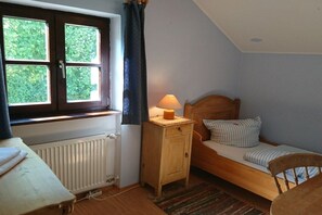 Ein kleines Schlafzimmer mit einem Einzelbett, einem Nachttisch, einem Fenster mit Vorhängen und einer Heizung.