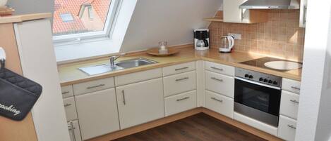A modern kitchen with a skylight, a coffee maker, and a stove.
