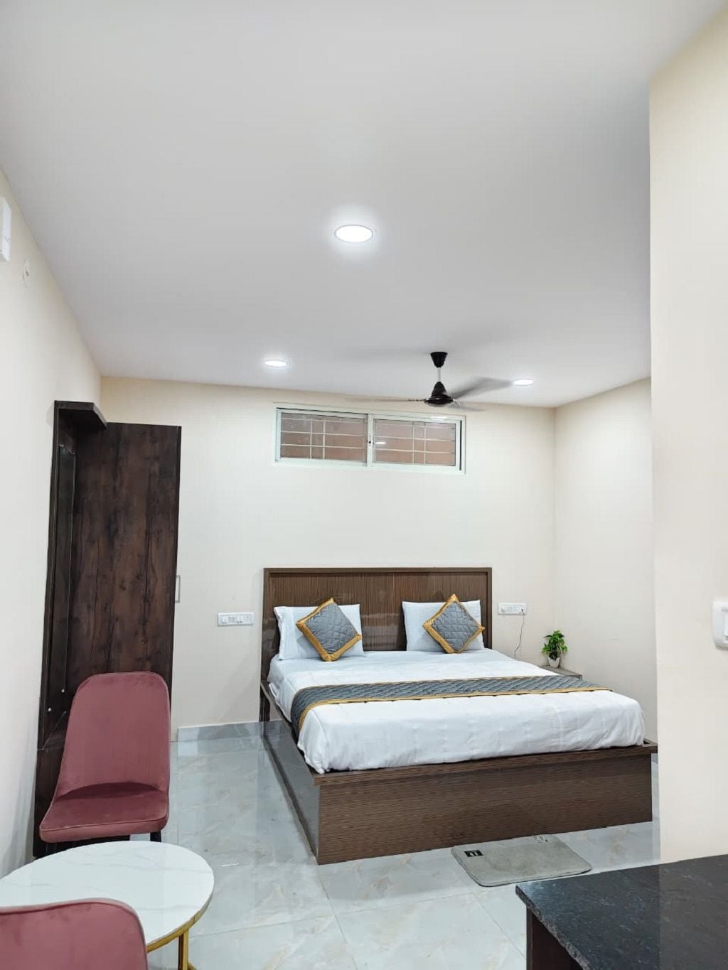 Ein Schlafzimmer mit Bett, Deckenventilator, Fenster und einem kleinen Tisch.