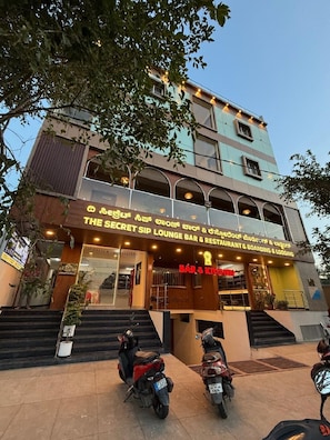 Un edificio de varios pisos con bar y restaurante en la planta baja, que presenta una escalera y motocicletas estacionadas.