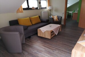 A modern living room with a sofa, a coffee table, and a dining area with a table and chairs. - Rivaner with roof terrace (Burg)