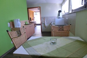 A kitchen with a dining table, wicker chairs, a coffee maker, and a toaster. - Rivaner with roof terrace (Burg)