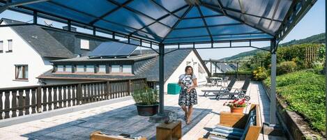 An outdoor patio with wooden furniture and a covered area.