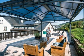 An outdoor patio with wooden furniture and a covered area. - Rivaner with roof terrace (Burg)