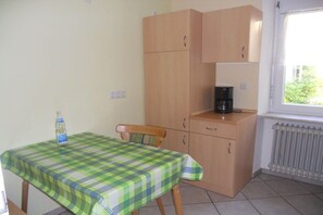 A small kitchenette with a table and chairs, a radiator, and a window. - Holiday apartment with 1 bedroom (St. Märgen)