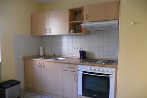 Eine kleine Küche mit Herd, Backofen und Spüle.
