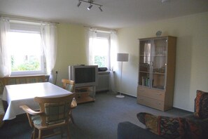A living room with a television, a cabinet, a table, and a sofa. - Holiday apartment with 1 bedroom (St. Märgen)