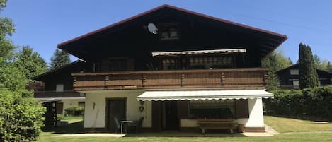 A two-story chalet with a sloped roof, a covered porch, and a satellite dish.