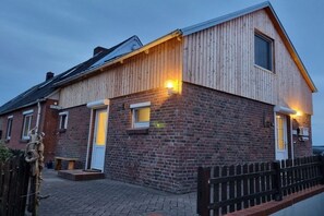A two-story building with a brick facade and a wooden extension. - North Sea house with pirate's nest (Nordstrand)