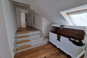 Un escalier avec une finition en bois et un mur blanc agrémenté d’une fenêtre.