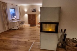 Ein Zimmer mit Holzboden, einem Schreibtisch mit Stuhl, einem Schrank und einem Kamin.