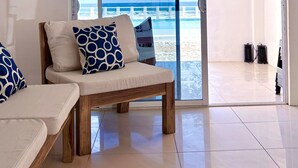 Uma sala de estar moderna com uma grande porta de vidro deslizante que dá para a praia.