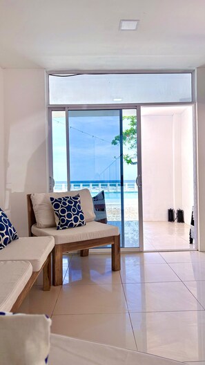 A modern living room with a large sliding glass door leading to a beach view. - Spacious 5-bedroom house in charming La Libertad with AC (La Libertad)
