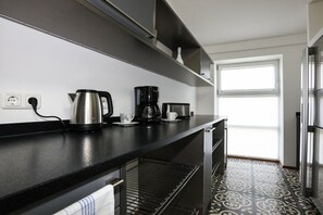 Eine moderne Küche mit schwarzem Arbeitsplatz, Edelstahlgeräten und einem gemusterten Boden.