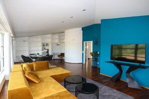 Ein modernes Wohnzimmer mit einer Couch, einem Couchtisch und einem Fernseher auf einem Schrank.