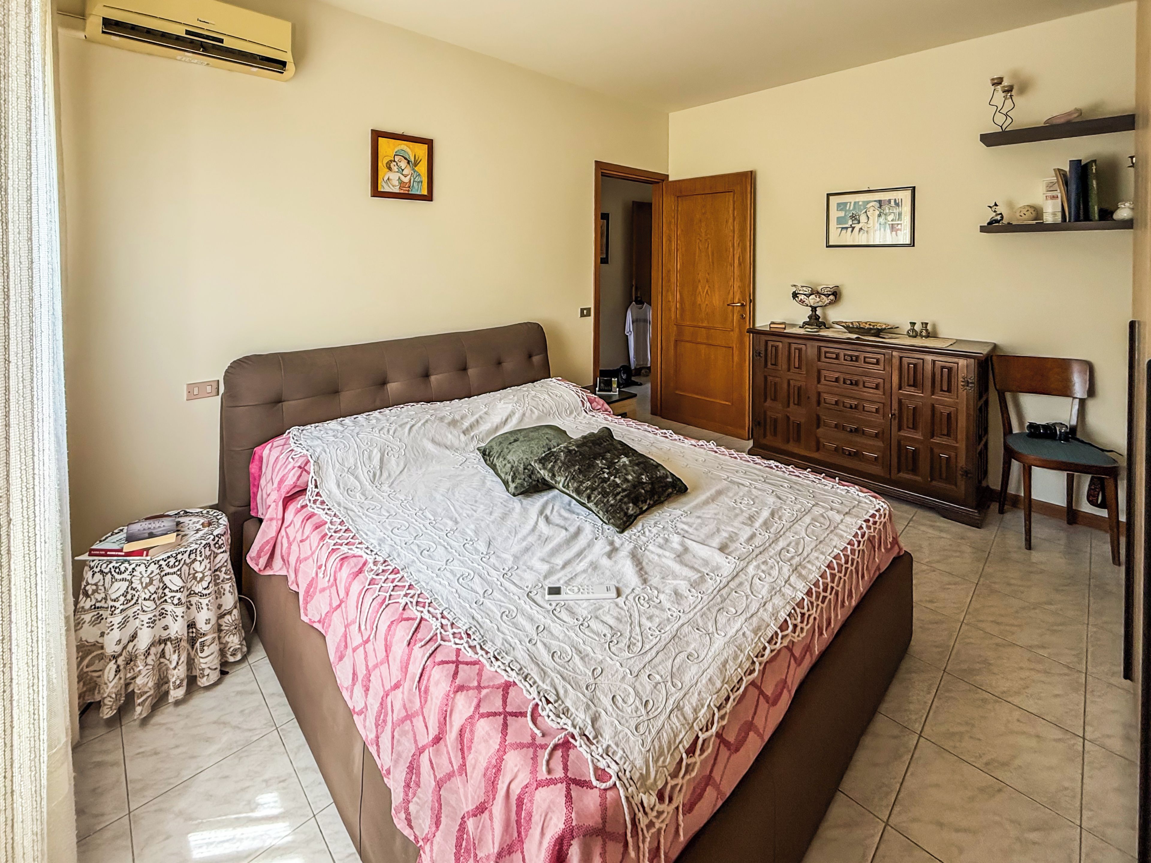 A bedroom with a bed, a dresser, a chair, and a door.