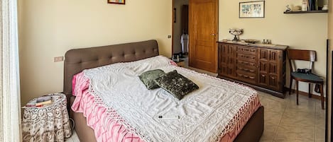 A bedroom with a bed, a dresser, a chair, and a door.