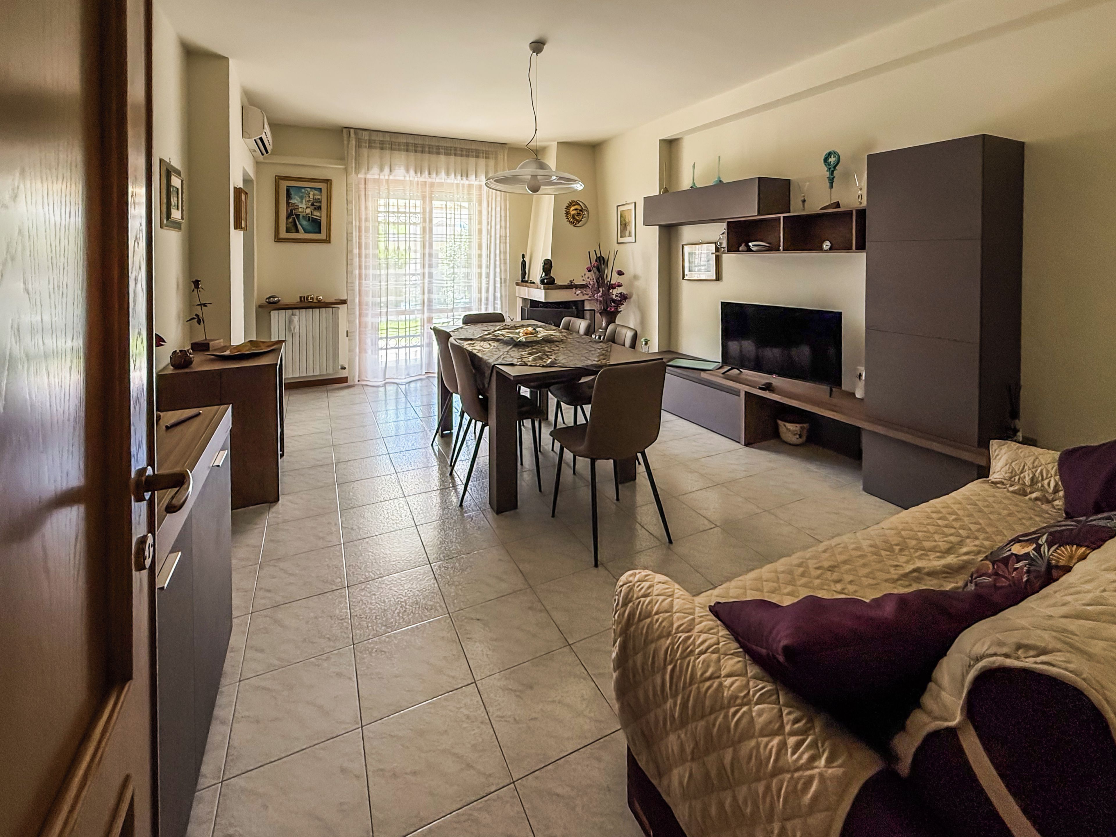 A modern living space with a dining area, a sofa, and a television.