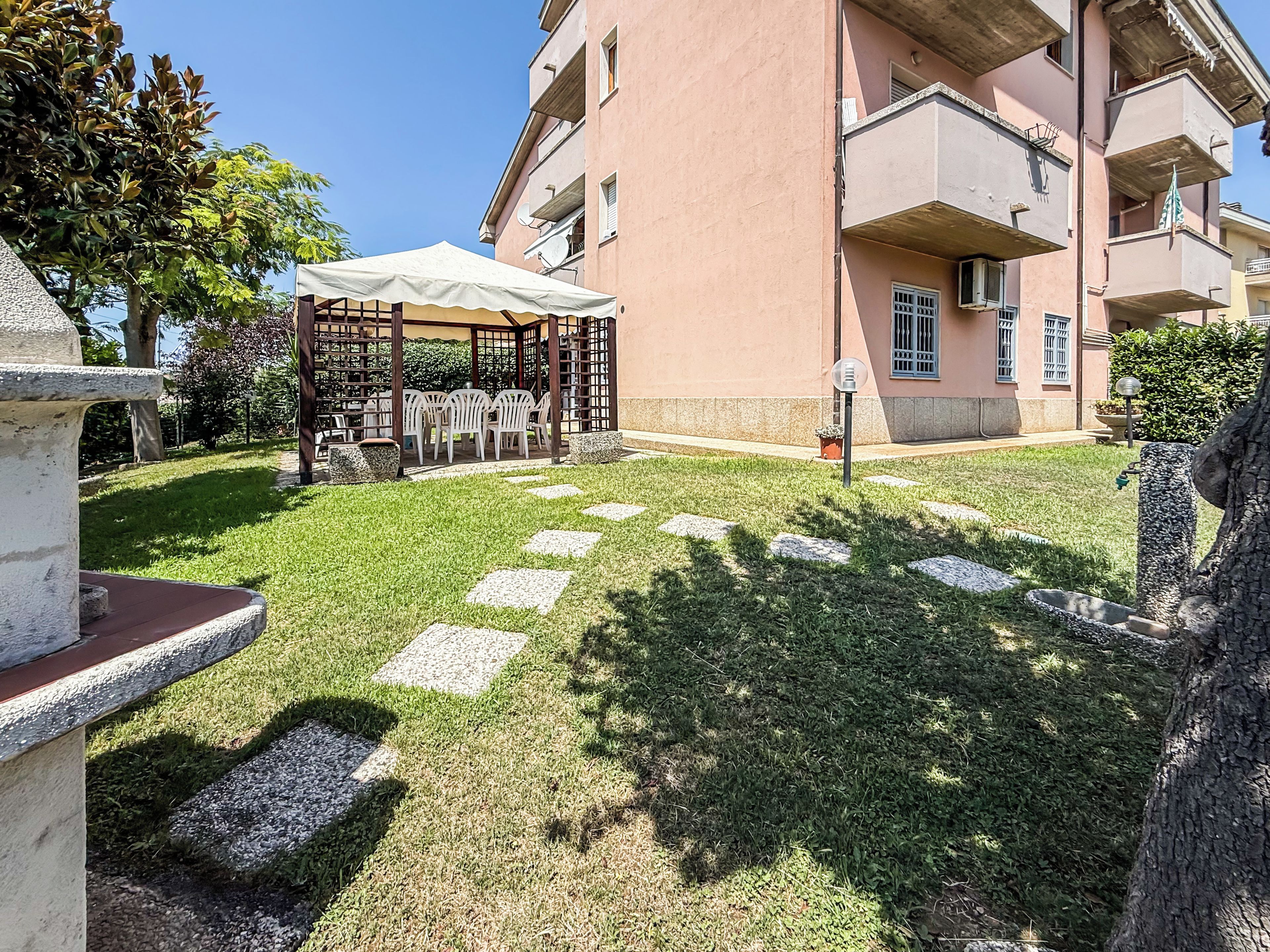 A courtyard with a pergola, outdoor seating, and a building with balconies.
