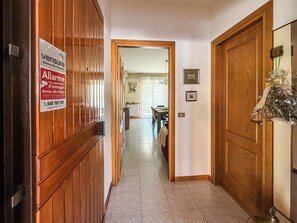 A hallway with wooden doors, a sign on the left, and a dining area in the background. - Casa Armando (Passignano sul Trasimeno)