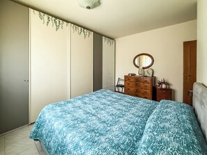 A bedroom with a bed, dresser, chair, and a wardrobe. - Casa Armando (Passignano sul Trasimeno)