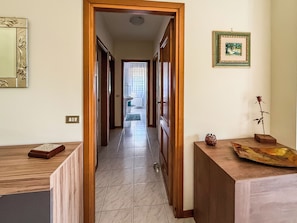 A hallway with wooden doors leading to a bathroom and a living area. - Casa Armando (Passignano sul Trasimeno)