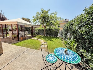 A patio area with a table and chairs, a covered seating area, and a well-maintained lawn. - Casa Armando (Passignano sul Trasimeno)