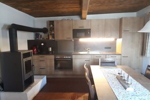 Eine kompakte Küche mit einer zentralen Kochinsel, integrierten Geräten und einer Holzbalkendecke.