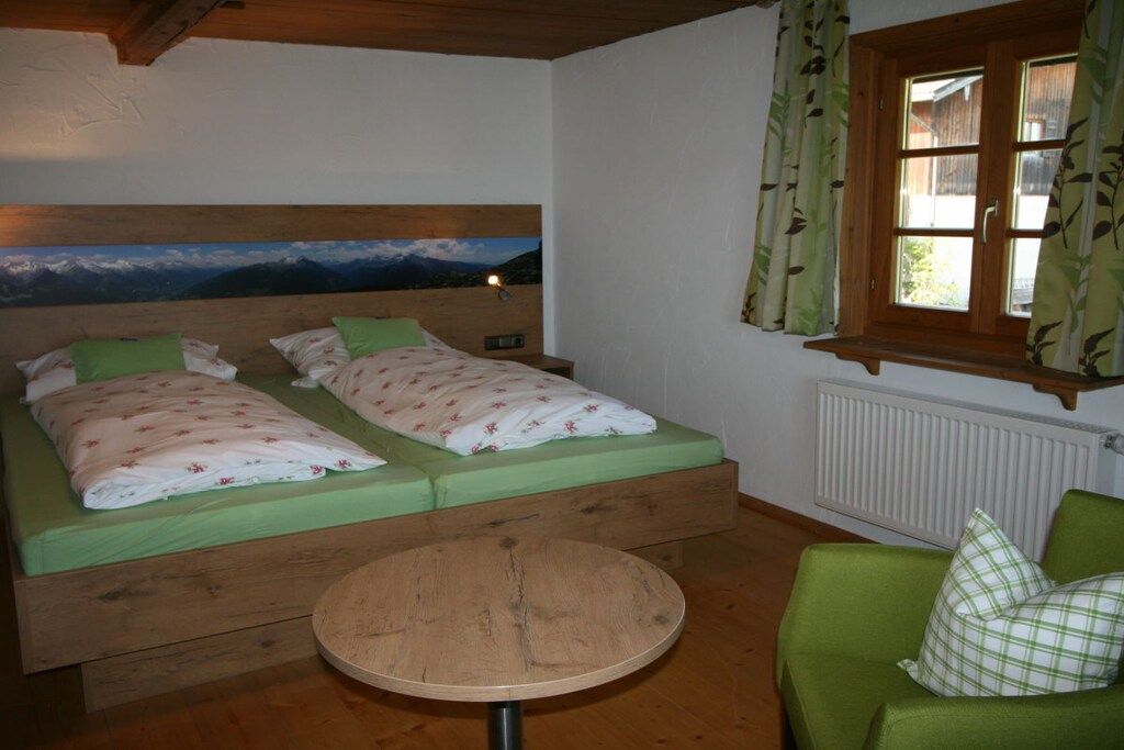 Ein Zimmer mit einem Bett, einem runden Tisch und einem grünen Sofa.