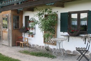 Ein rustikales Gebäude mit einer Holztür, einem kleinen Tisch und einem Stuhl davor.