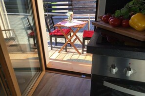 Eine Küche mit einer Schiebetür zu einer Terrasse im Freien, komplett mit Tisch und Stühlen.