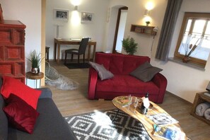 Ein Wohnzimmer mit einem roten Sofa, einem grauen Sofa, einem Holztisch mit Zeitschriften und einem gemusterten Teppich.